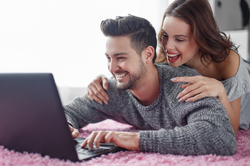 Happy young couple online shopping by laptop at home